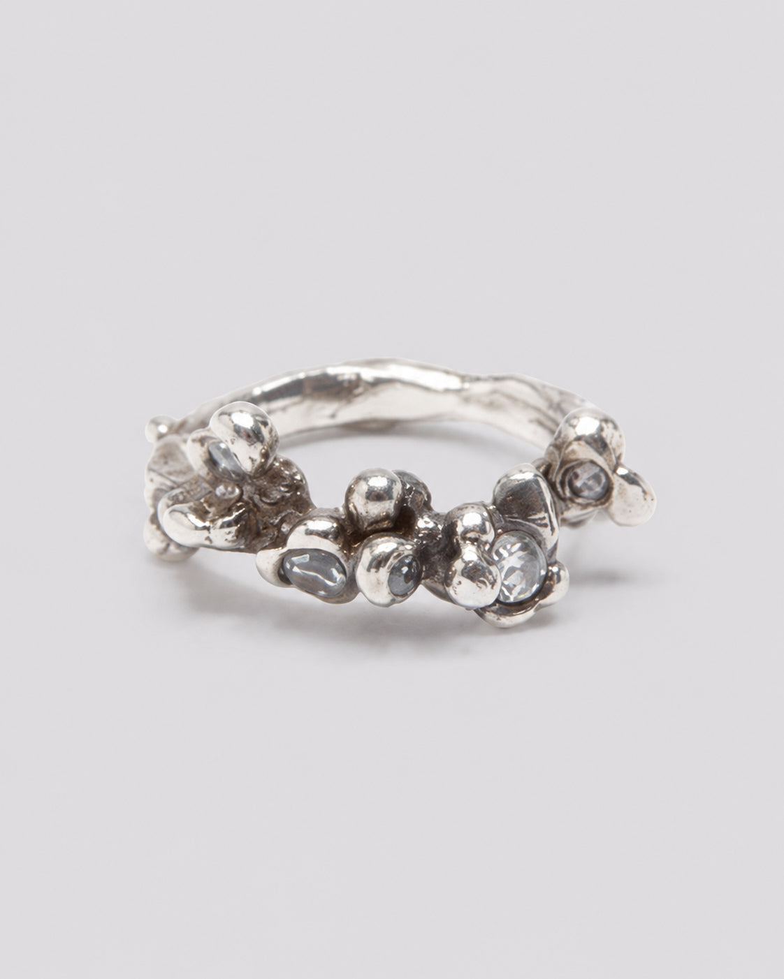 A silver ring with an organic, textured, fluid design featuring small clear gemstone topaz