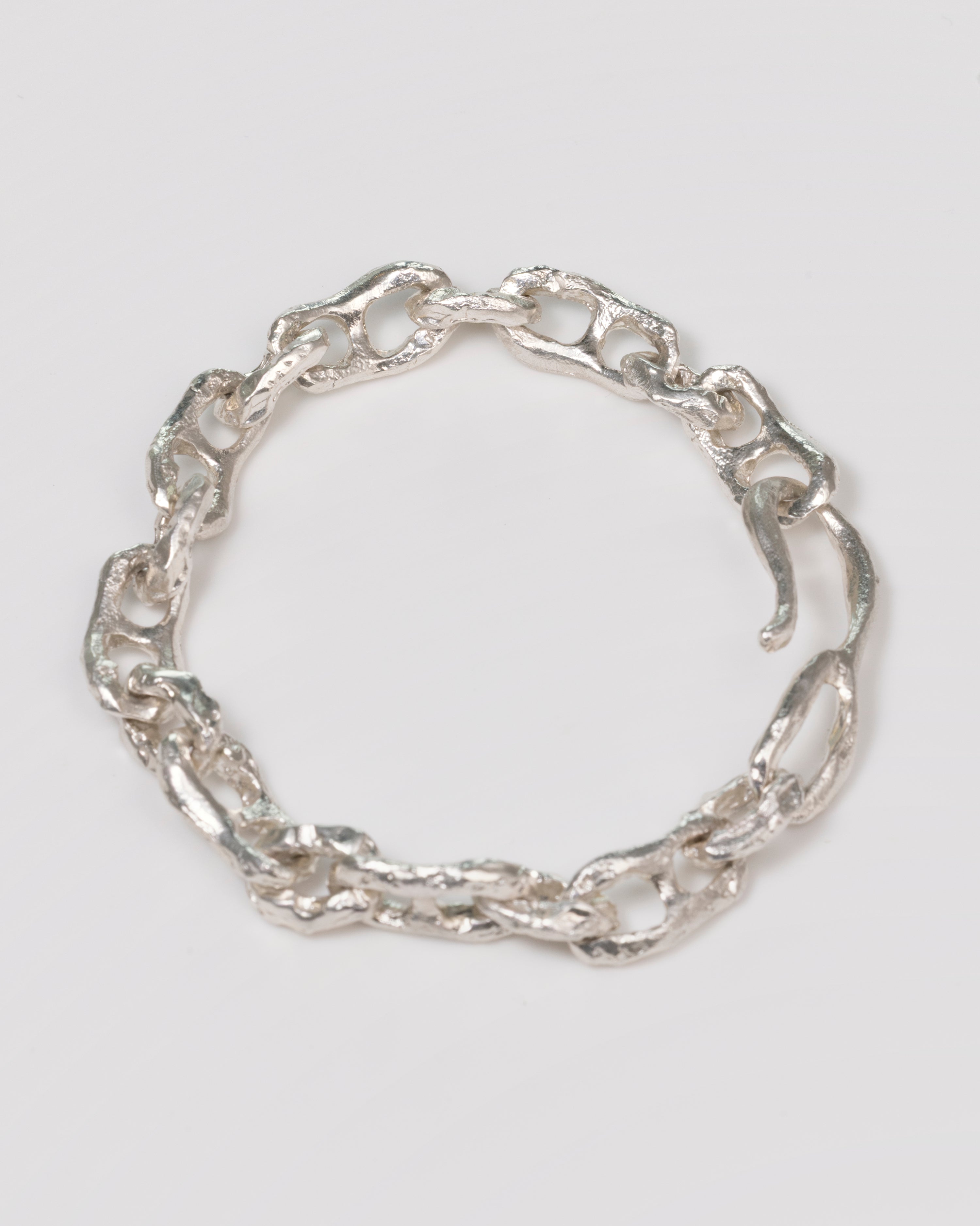 A textured silver chain bracelet with a unique wavy, organic link design, displayed on a neutral light gray background.