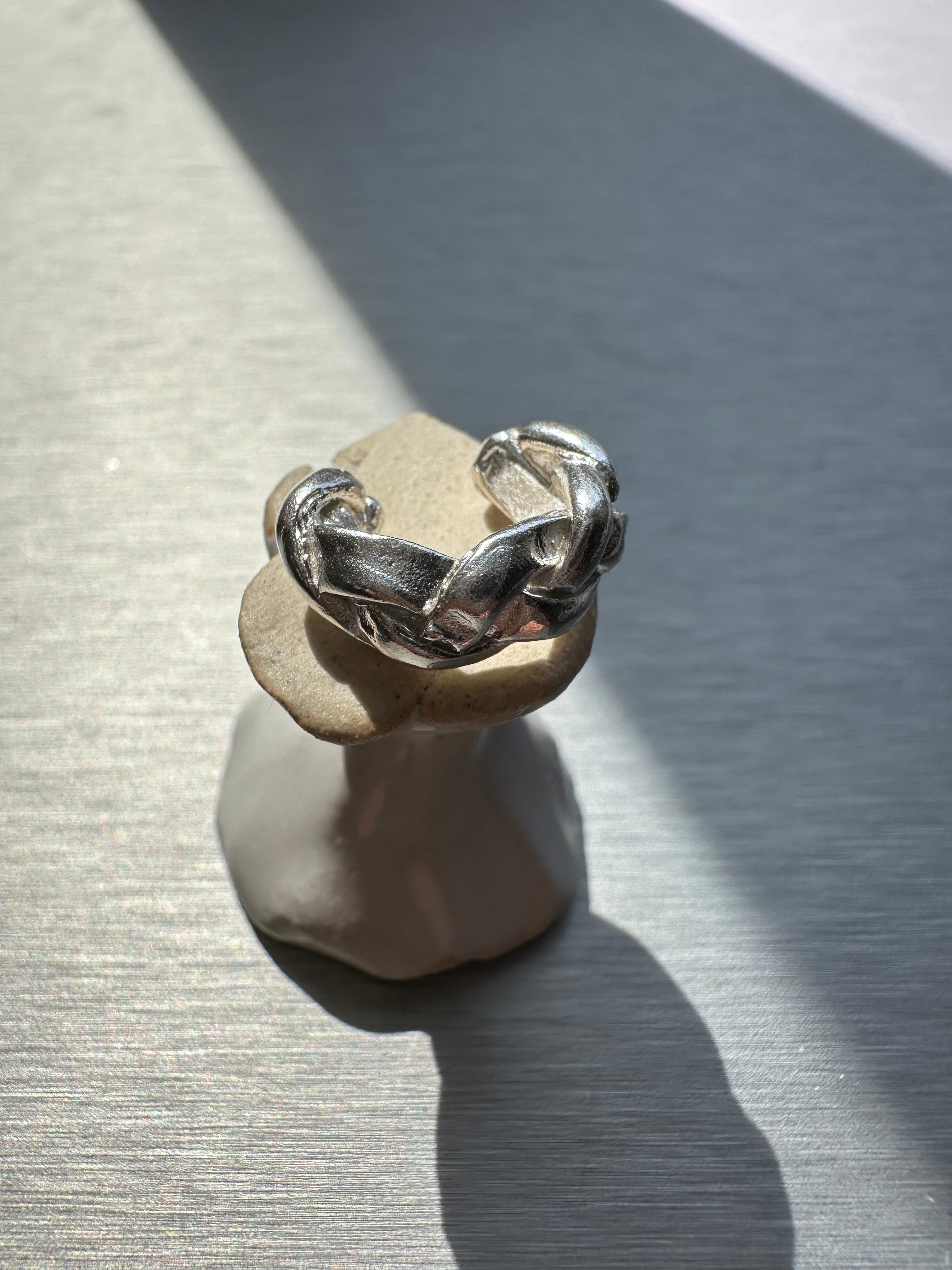 Silver ring on a textured surface with a neutral background